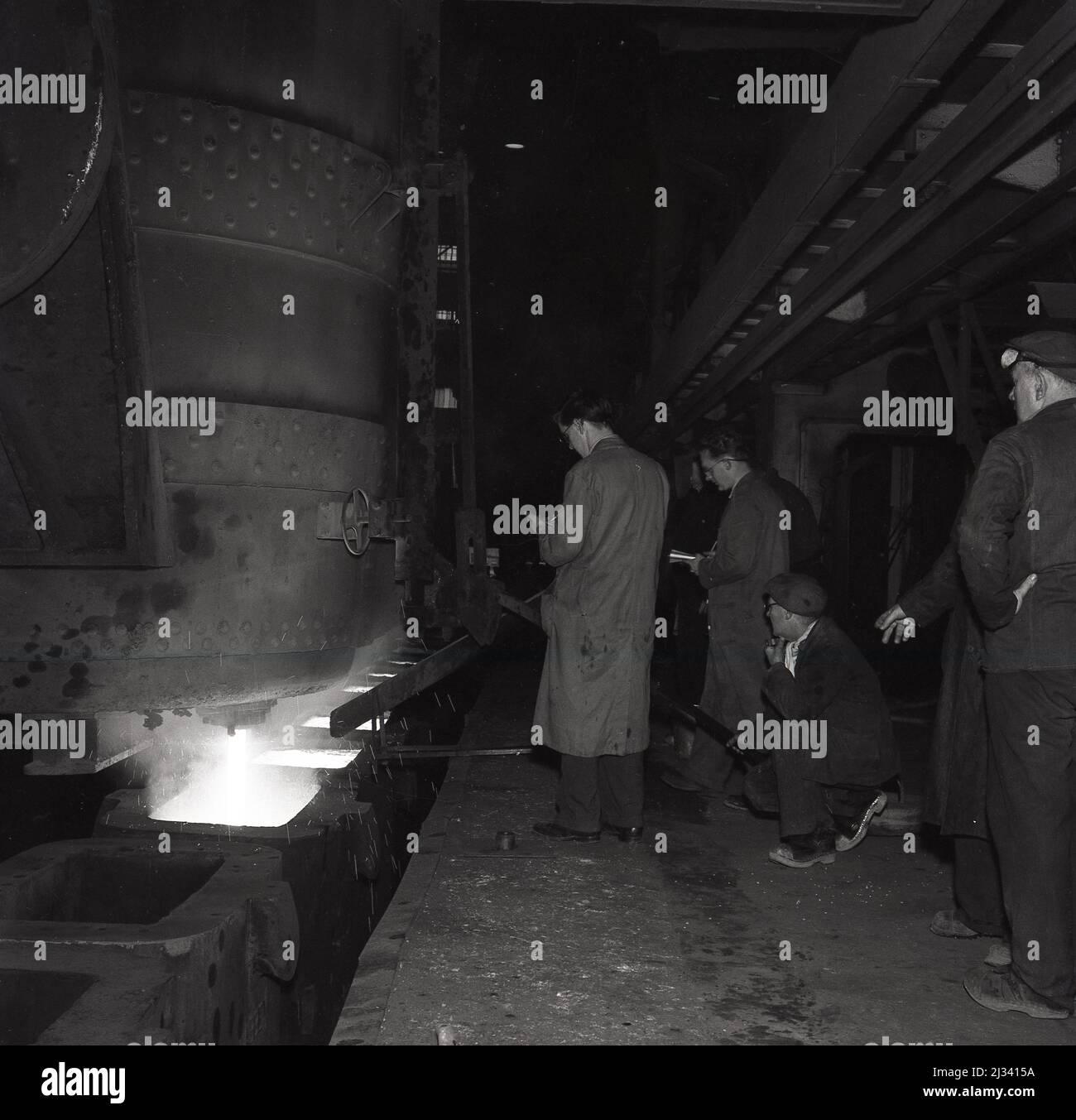 1950s, historique, sidérurgique et directeur de travaux à côté d'un haut fourneau supervisant la production de liquide de fer fondu à l'usine de la Steel Company of Wales, Abbey Works, Port Talbot, pays de Galles, Royaume-Uni. Banque D'Images