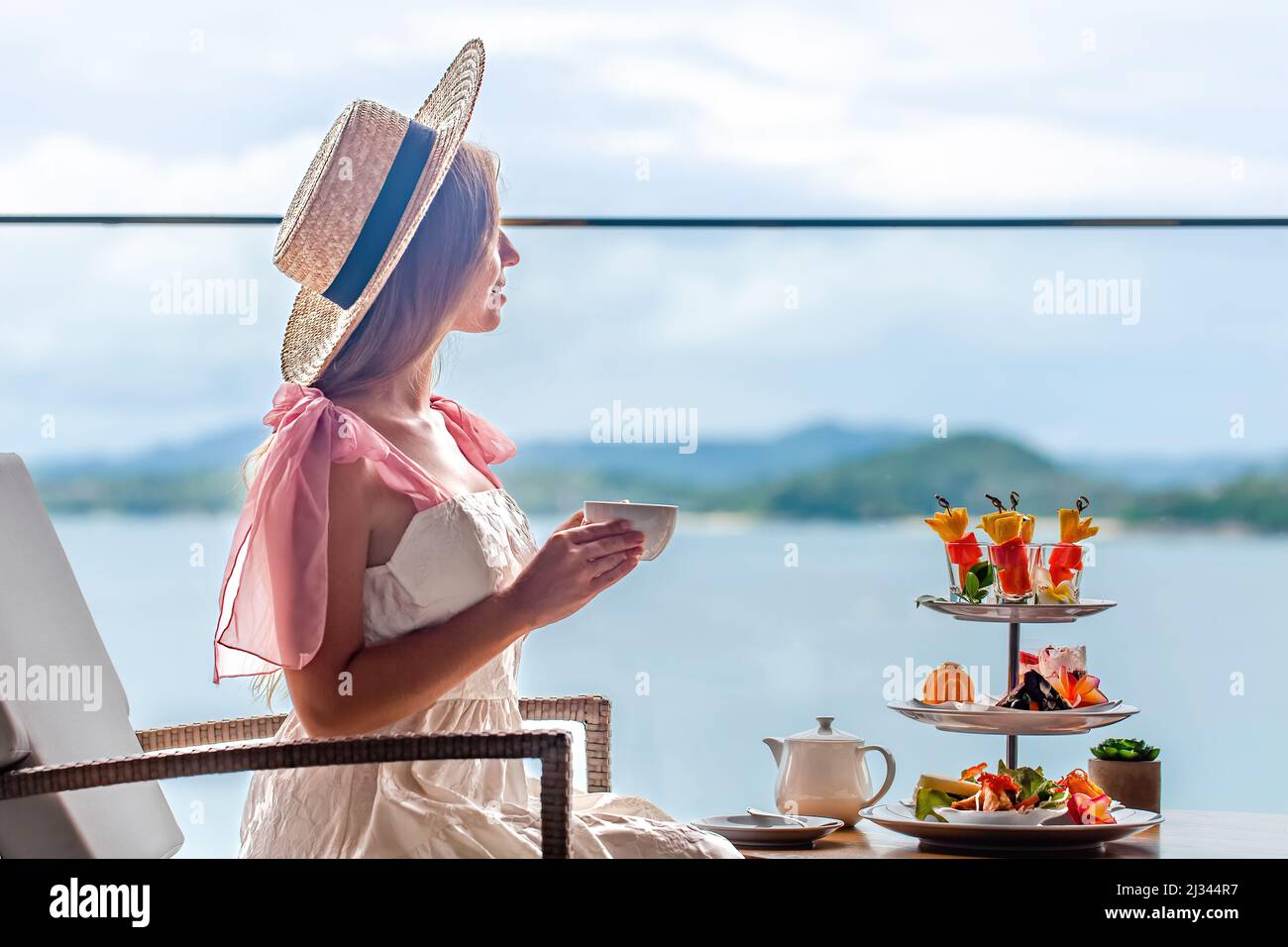 Jeune femme en robe blanche qui boit le thé de l'après-midi avec divers bonbons Banque D'Images