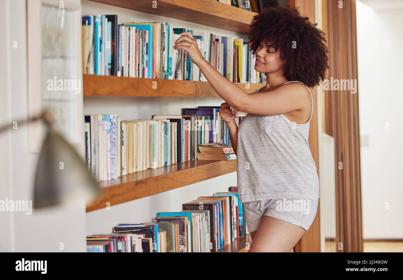 Arbres tatoués pour un monde dans un classeur. Photo d'une jeune femme attirante parcourant un rayon de livres à la maison. Banque D'Images