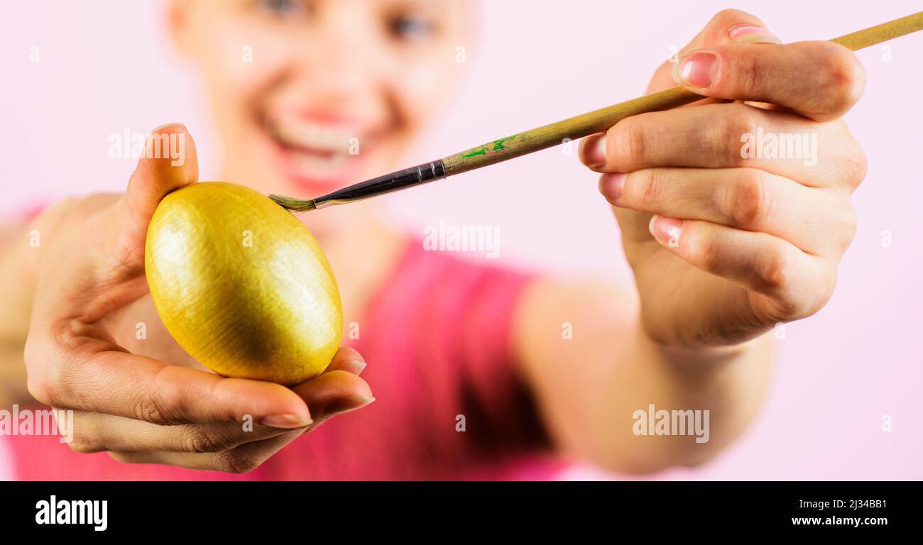 Le jour de Pâques. Femme souriante peignant un œuf. Lapin avec œuf jaune et pinceau. Banque D'Images