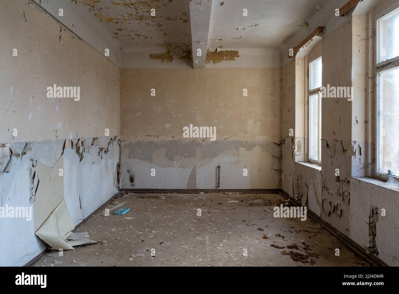 Vider la vieille chambre dans un bâtiment abandonné. La lumière de la fenêtre brille. La peinture s'écaille des murs avant la rénovation. Intérieur du chantier de construction. Banque D'Images