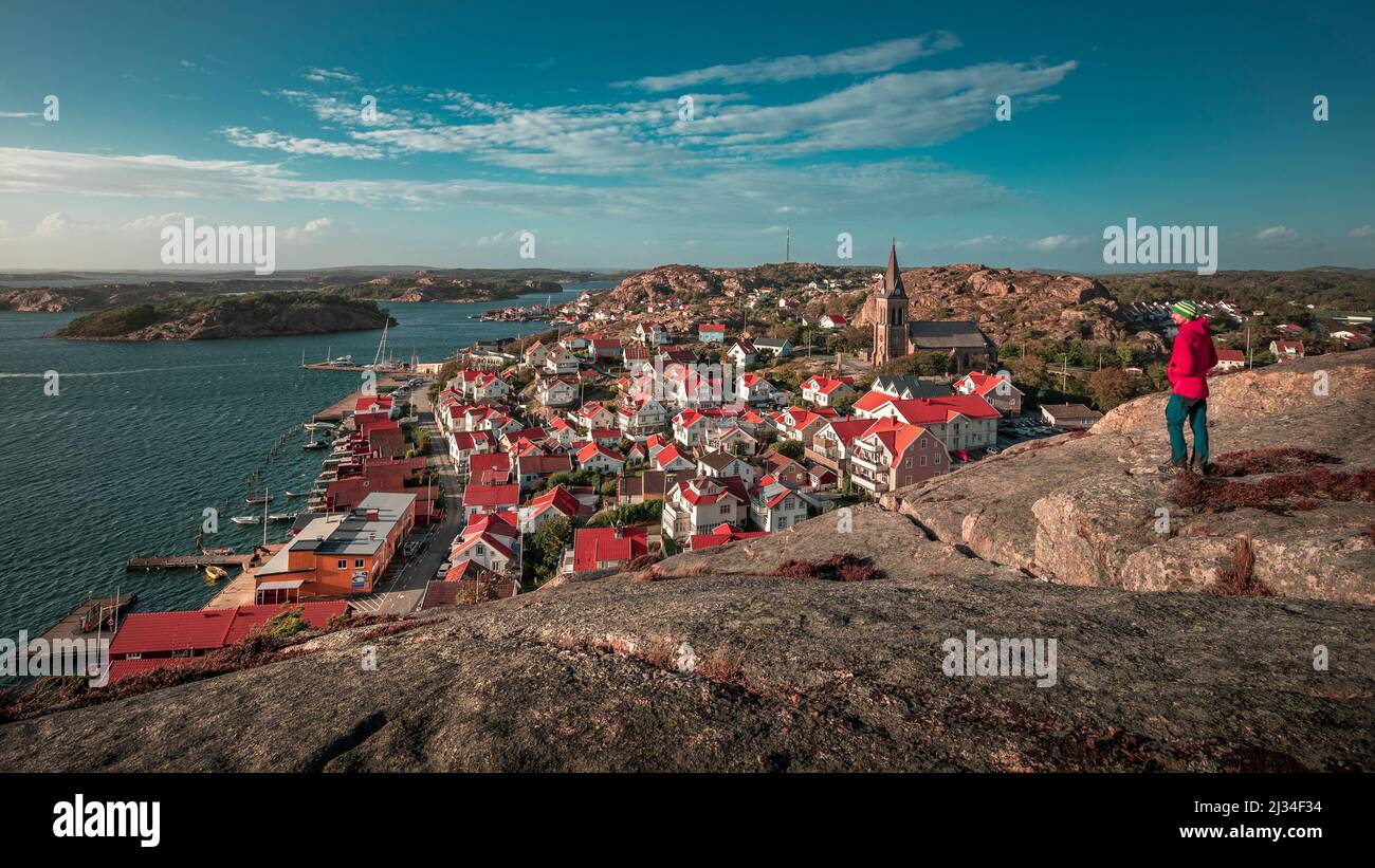 Mann blickt über Küste und Dorf Fjällbacka vom Berg Vetteberget mit Felsspalte von oben BEI Tag mit sonne und blauem Himmel an der Westküste in Schweden Banque D'Images