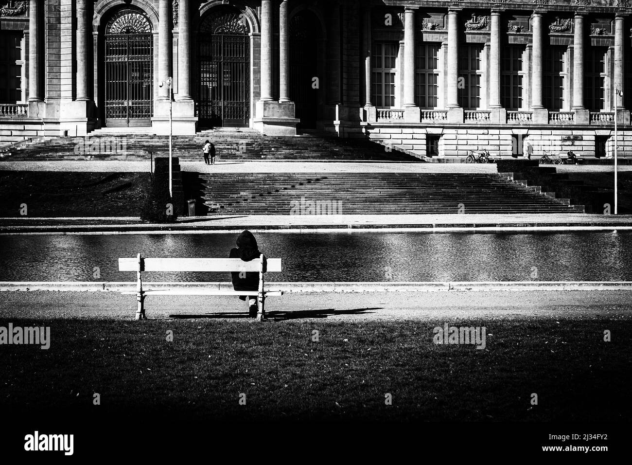 Garçon sur un banc en face de l'ancien bâtiment classique Banque D'Images