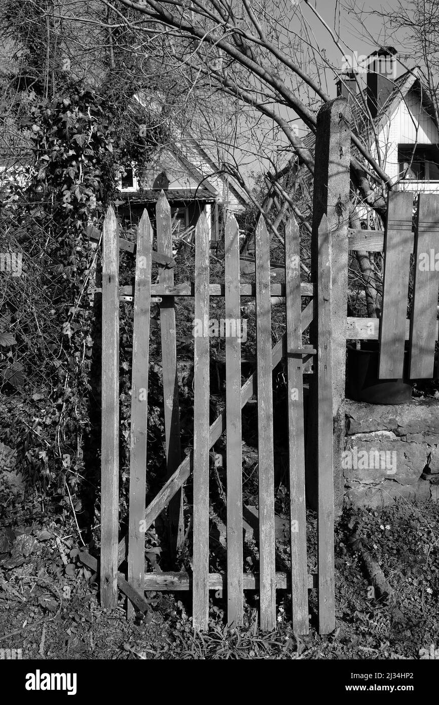 Une clôture en bois cassée devant une maison rurale Banque D'Images