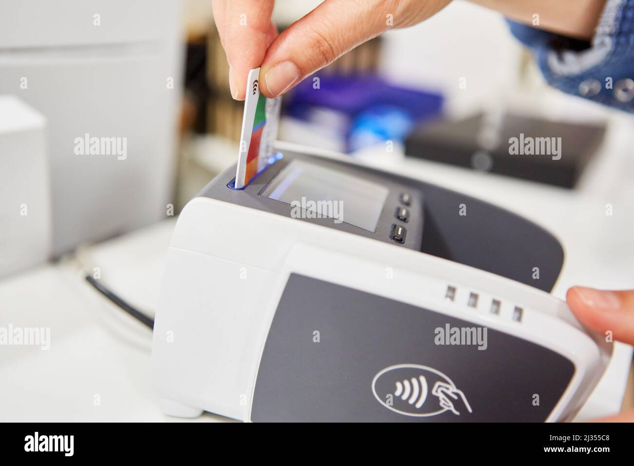 La main insère la carte client ou la carte de crédit dans un terminal de carte pour un paiement sans espèces Banque D'Images
