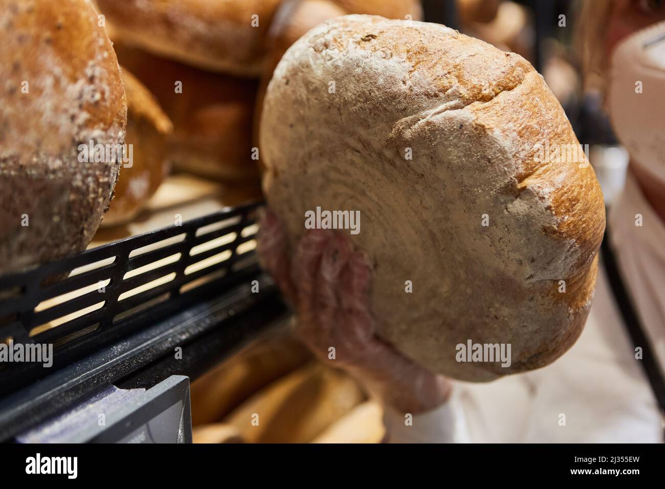Le client prend un pain de l'étagère de la boulangerie comme un concept d'aliment de base Banque D'Images