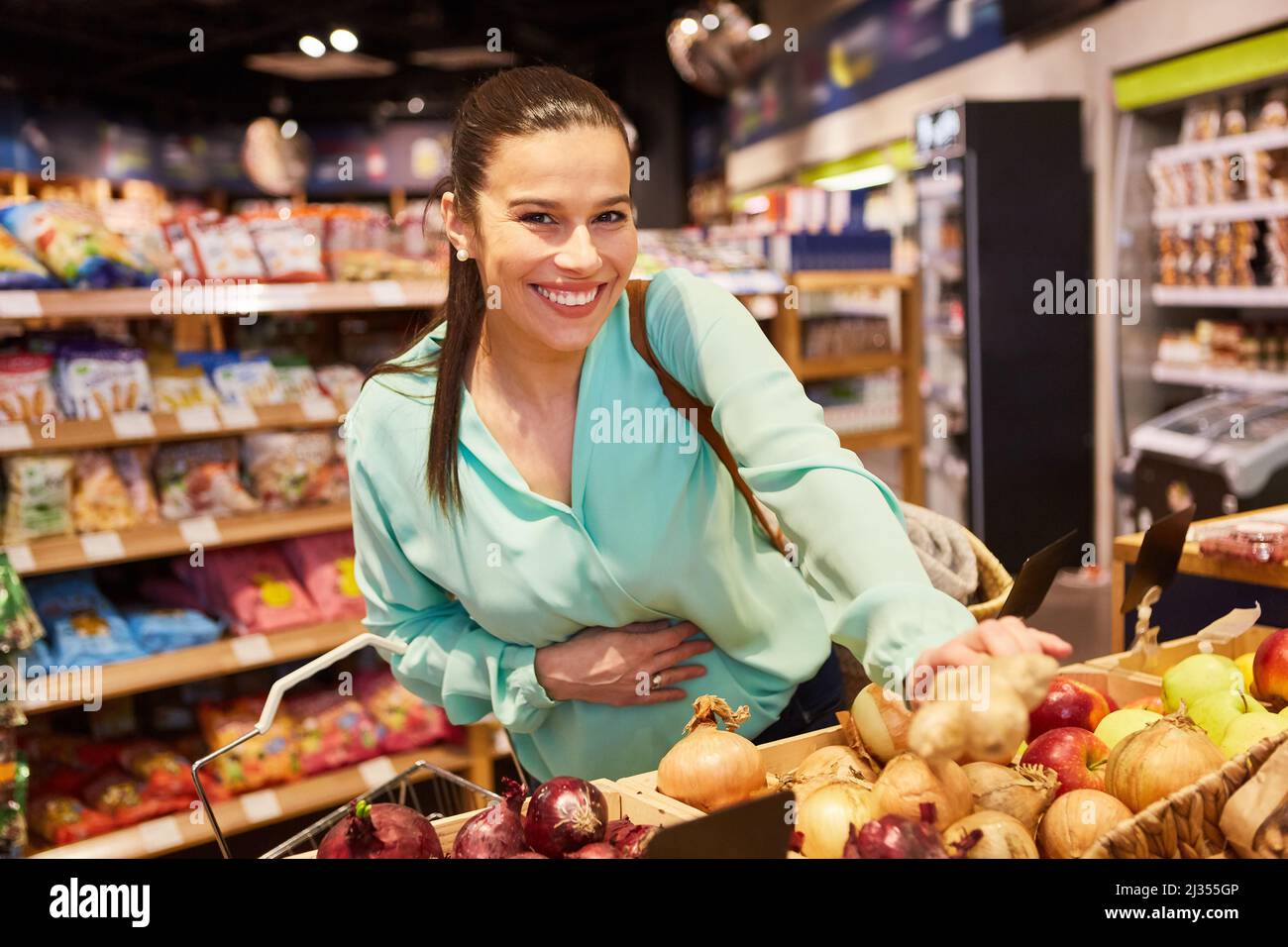 Une jeune femme en tant que client heureux magasiner pour des légumes dans le supermarché ou l'éco-boutique Banque D'Images