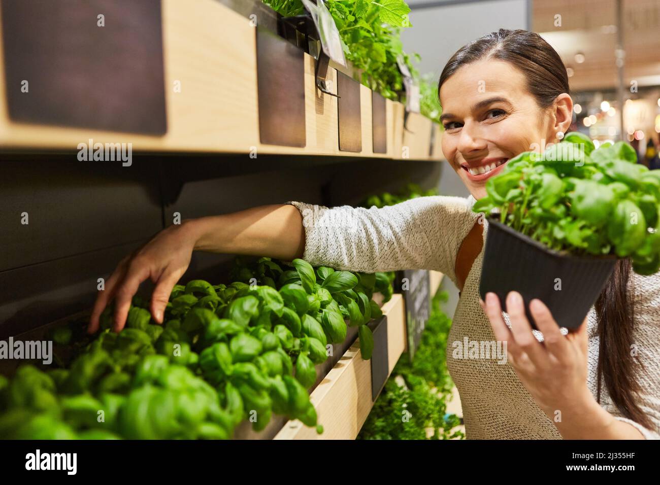 Femme en tant que client satisfait dans le supermarché dans le département des herbes avec le basilic dans sa main Banque D'Images