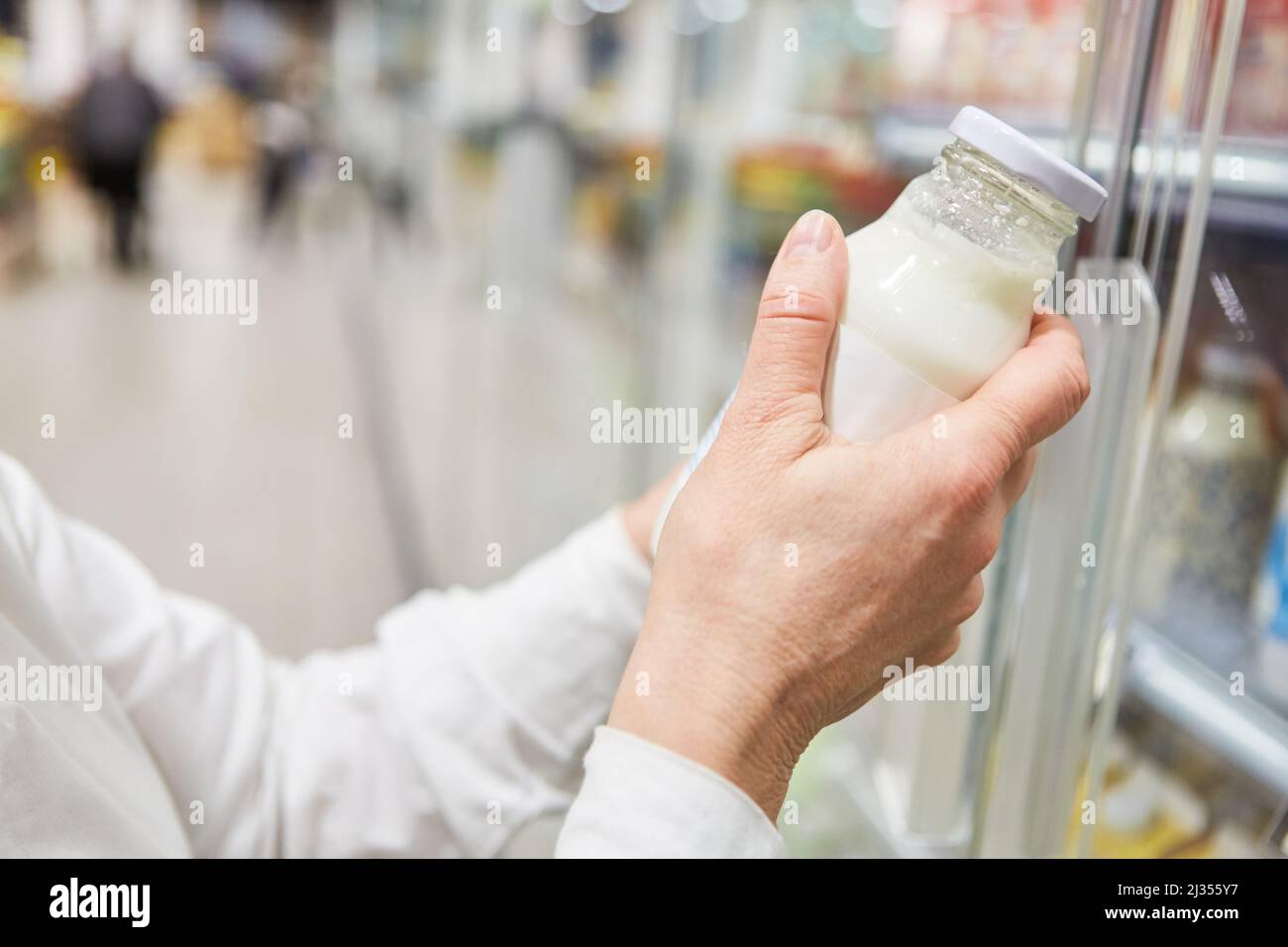 La main d'un client lorsqu'il recherche du lait d'amande ou du lait de soja dans la section réfrigérée du supermarché Banque D'Images