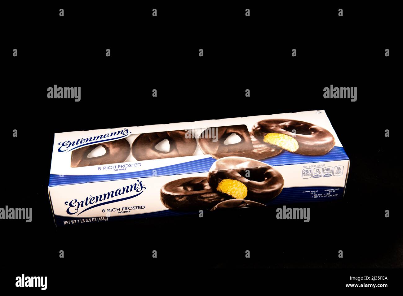 Une boîte de 8 beignets givrés d'Entenmann, avec un revêtement chocolat sur un centre de gâteau jaune doux isolé sur le noir Banque D'Images