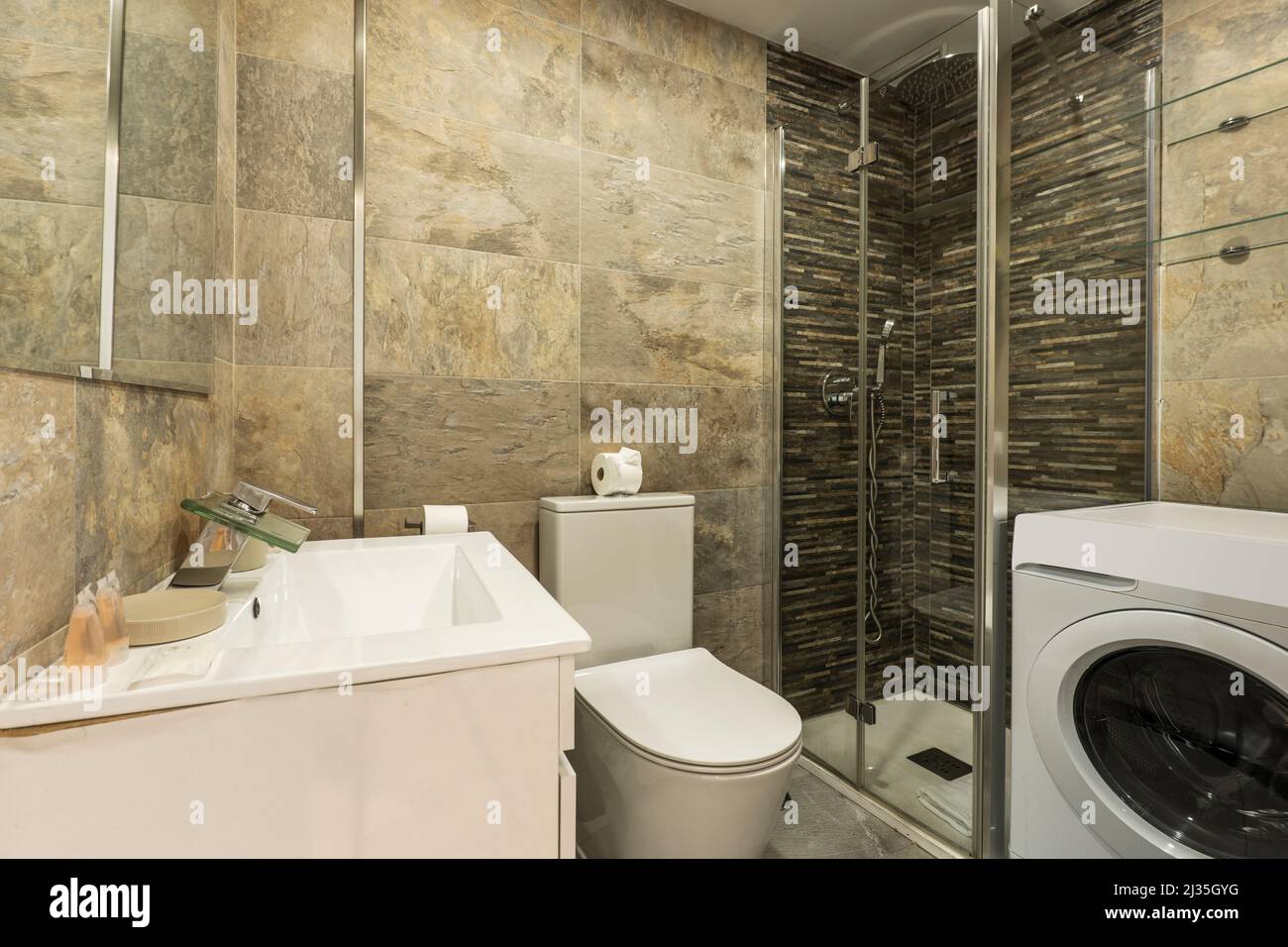 Cabine de douche avec écran en verre coulissant, lave-linge blanc, carrelage en marbre et évier en porcelaine blanche Banque D'Images