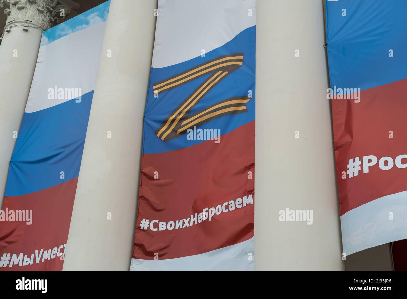 Artyom, Primorsky Krai, Russie - 27 mars 2022 : le drapeau de la Russie avec des slogans et des symboles patriotiques est exposé sur la façade du bâtiment. Banque D'Images