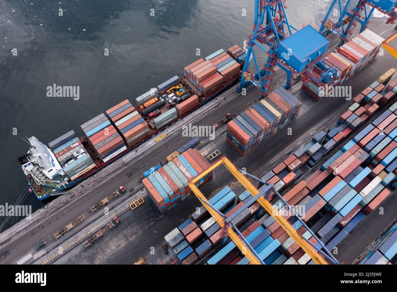 Vladivostok, Russie - 28 janvier 2022 : Vue de dessus du terminal des conteneurs du port maritime. En hiver, un bateau à conteneurs est en train de charger au quai. Banque D'Images