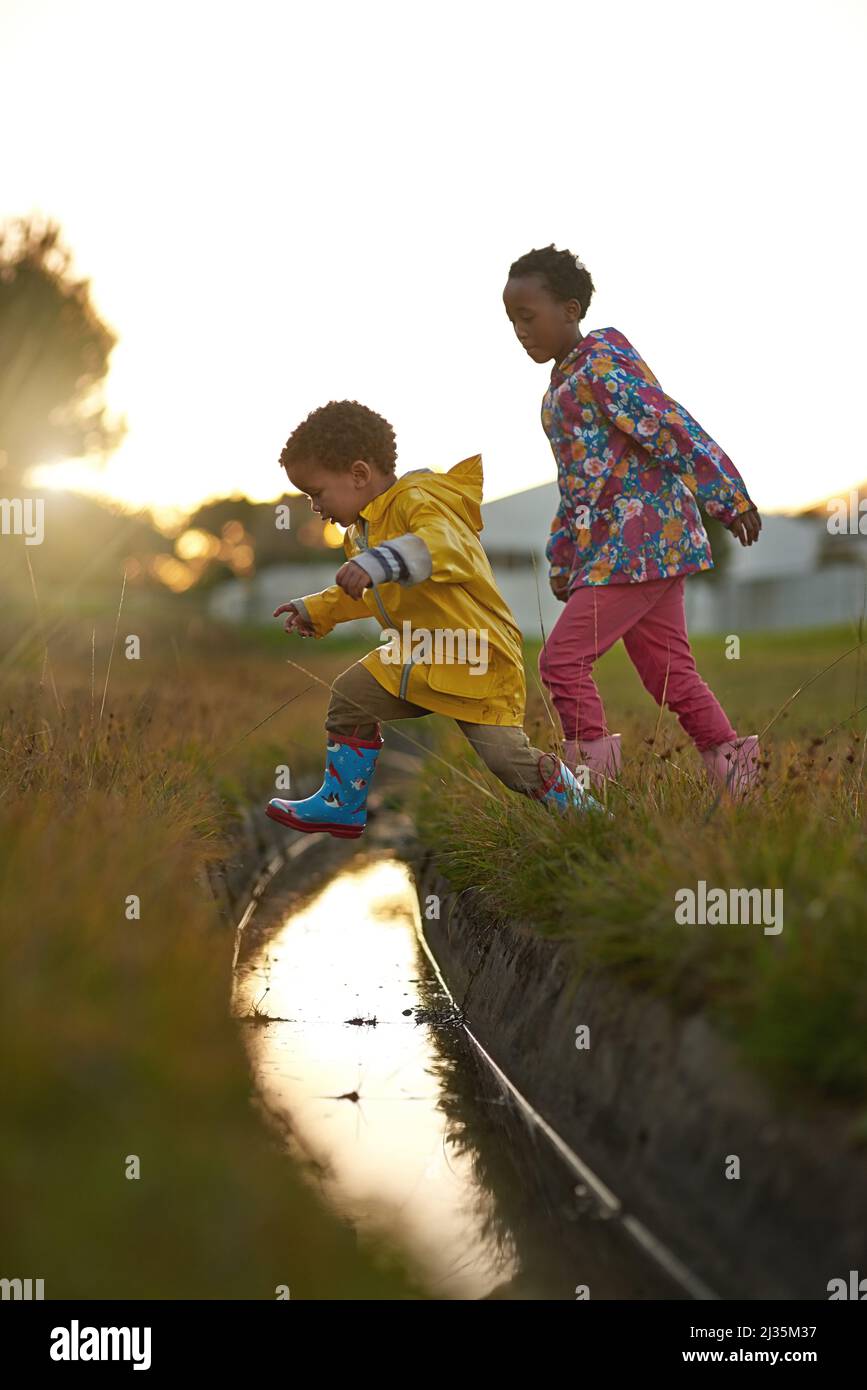 Montrant ses résultats. Photo d'un frère et d'une sœur qui sautent sur l'eau tout en jouant à l'extérieur. Banque D'Images