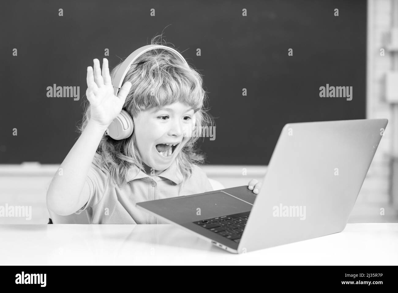 Excitée émotions des enfants.Enfant garçon dans un casque à l'aide d'un ordinateur portable et d'étudier en ligne avec un professeur de vidéo appel à l'école. Banque D'Images