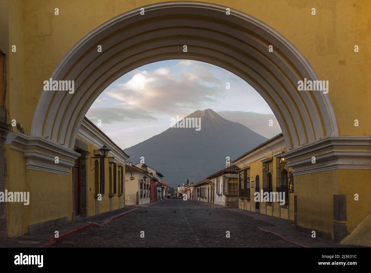 Lever du soleil à Antigua Guatemala, le volcan Agua, vu à travers l'arche de Santa Catalina, reçoit les premiers rayons de soleil Banque D'Images