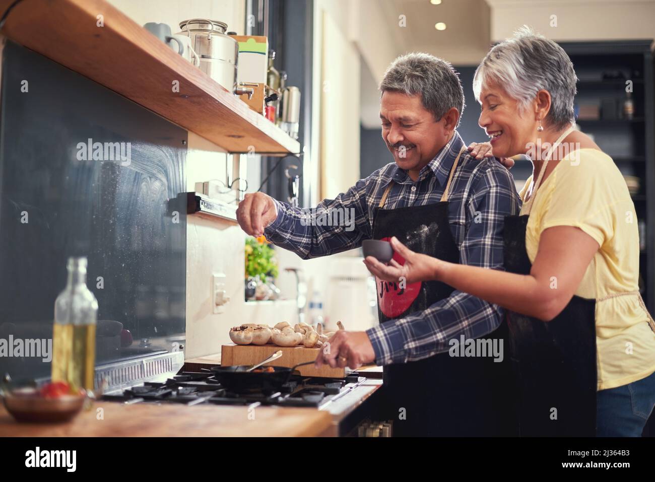 Plus de mains équivaut à moins de travail. Photo d'un couple heureux et mûr ajoutant du sel à un plat tout en cuisinant ensemble à la maison. Banque D'Images