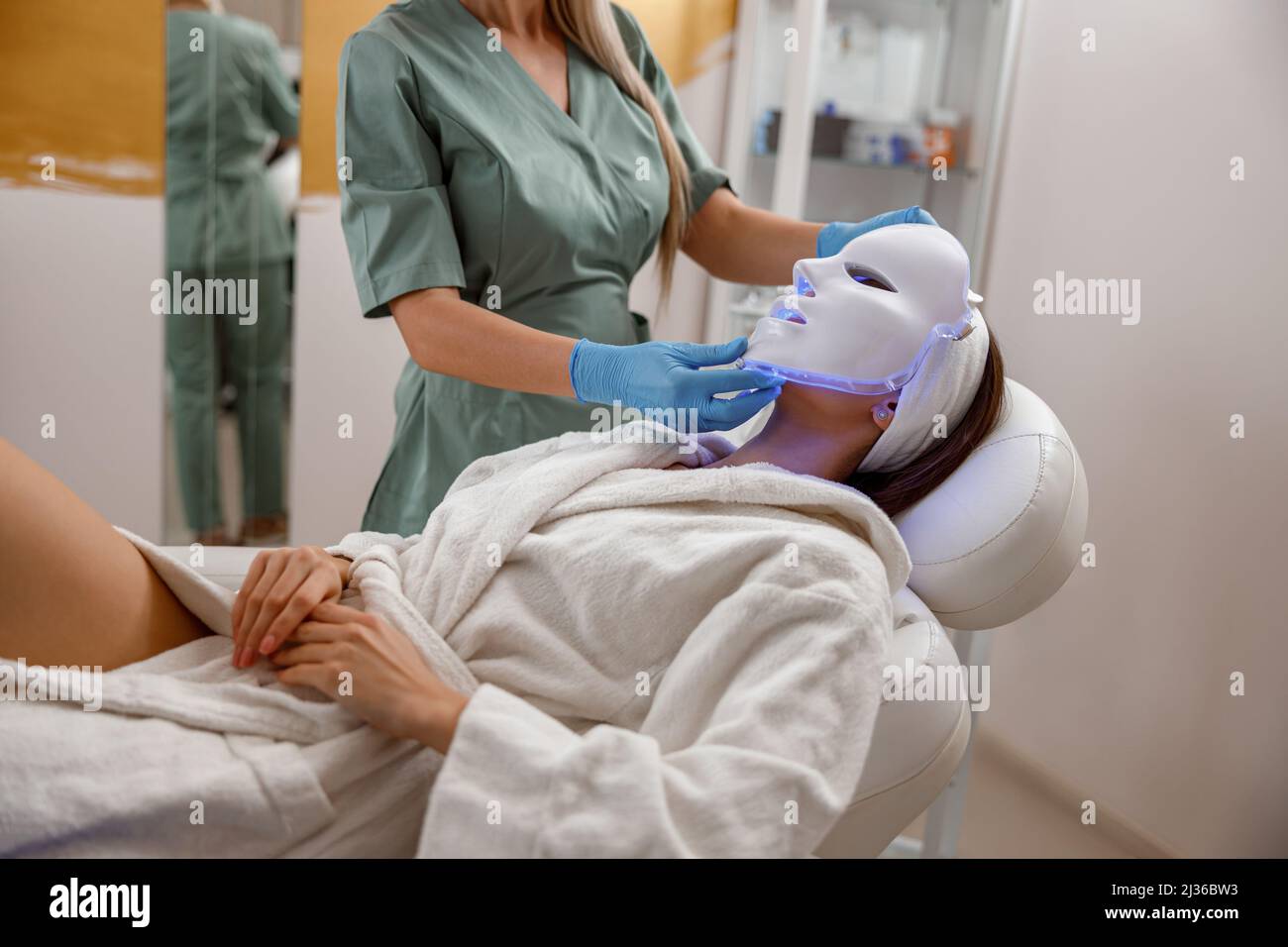 Femme qui obtient une procédure cosmétique avec un masque facial LED. Photonthérapie Banque D'Images Femme qui obtient une procédure cosmétique avec un masque facial LED. Photonthérapie Banque D'Images
