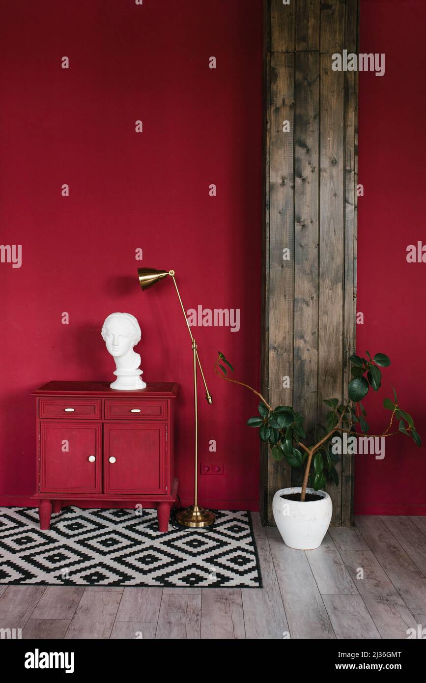 Sculpture d'une tête sur une commode rouge, une maison dans une casserole blanche dans un salon élégant Banque D'Images