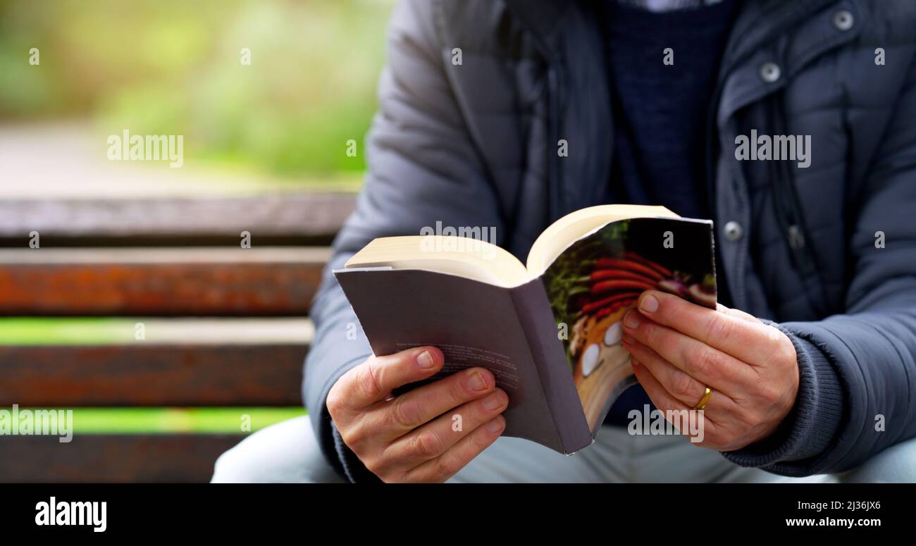 Voici ma partie préférée. Photo rognée d'un homme âgé méconnaissable lisant un livre par lui-même à l'extérieur d'un parc. Banque D'Images