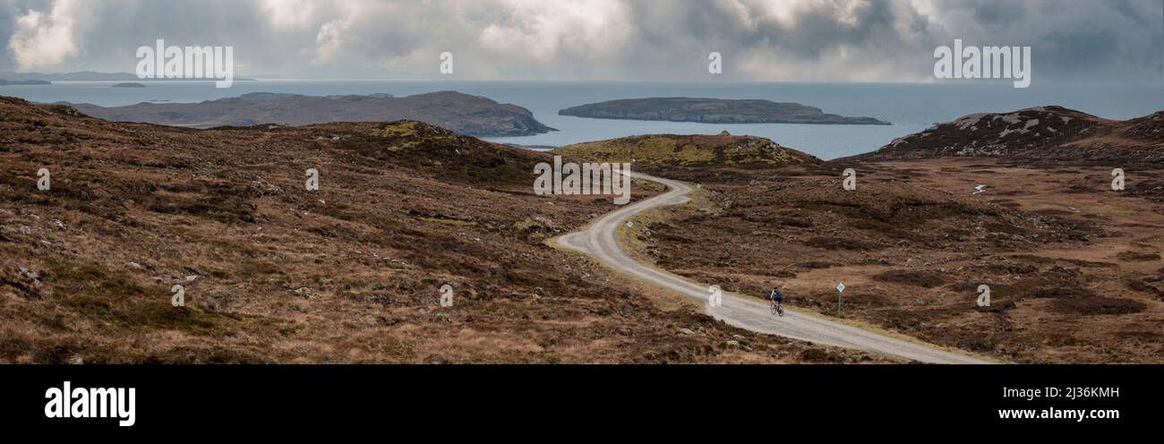 Un cycliste solitaire sur le Brae de Achnahaird, avec les îles Summer dans l'arrière-plan, côte ouest de l'Écosse. Banque D'Images