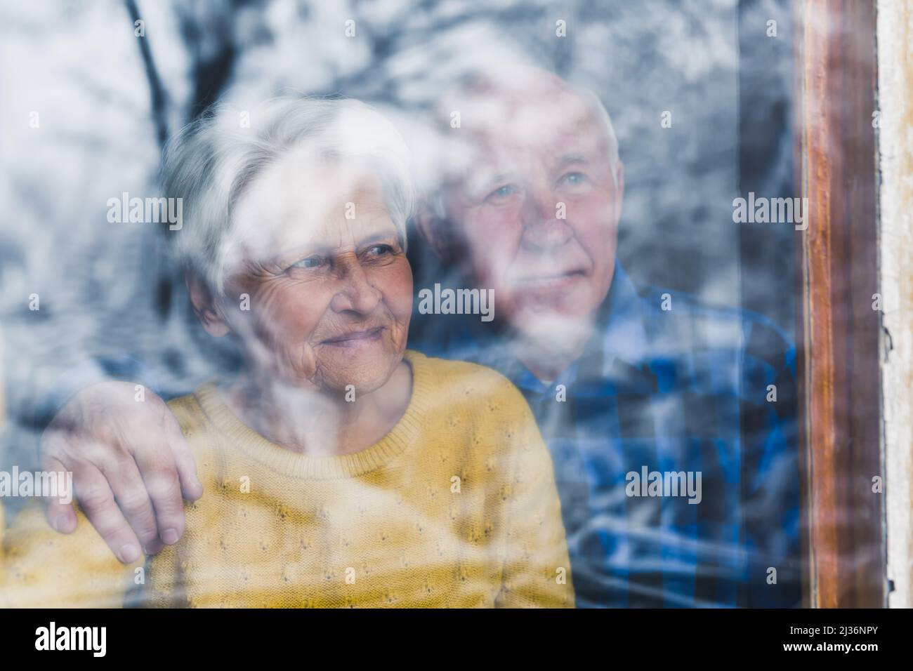 Senior couple marié âgé embrassant regardant par la fenêtre pendant l'hiver - l'amour et la convivialité à l'âge précoce . Photo de haute qualité Banque D'Images