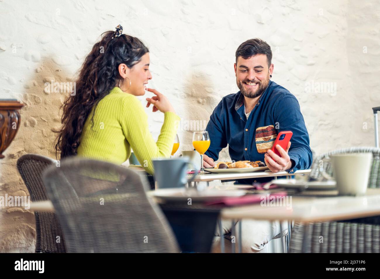 Couple touristique regardant le téléphone et prenant le petit déjeuner dans un restaurant de l'hôtel Banque D'Images