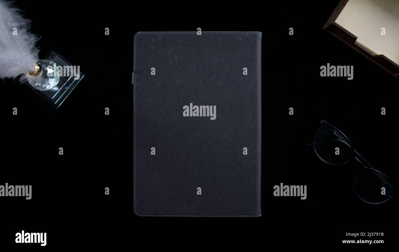 Concept table noire avec bloc-notes gris et lunettes, isolé sur fond noir, vue de dessus, décorations de table Banque D'Images