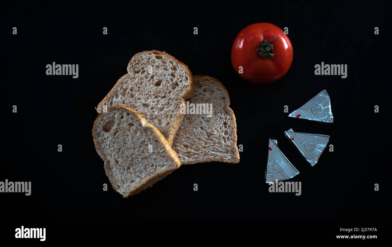 Tranches de pain et de tomate rouge au fromage triangle, sur table, nourriture conséchée, tranches de pain à la tomate isolées sur fond noir, vue du dessus Banque D'Images
