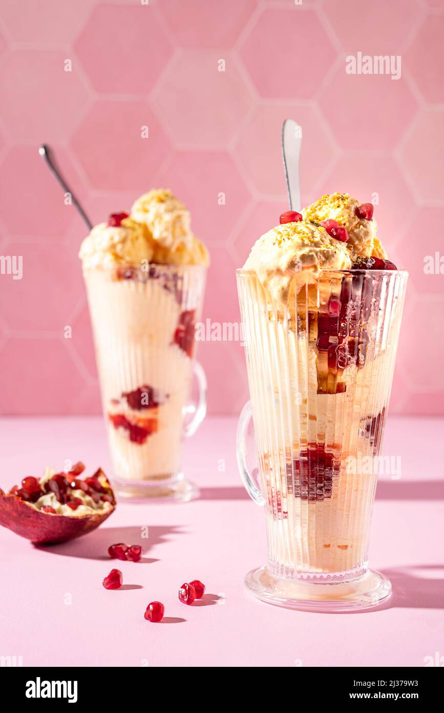 Milkshake à la crème glacée à la vanille garni de pistache fraîche et de graines de grenade sur fond rose Banque D'Images Milkshake à la crème glacée à la vanille garni de pistache fraîche et de graines de grenade sur fond rose Banque D'Images