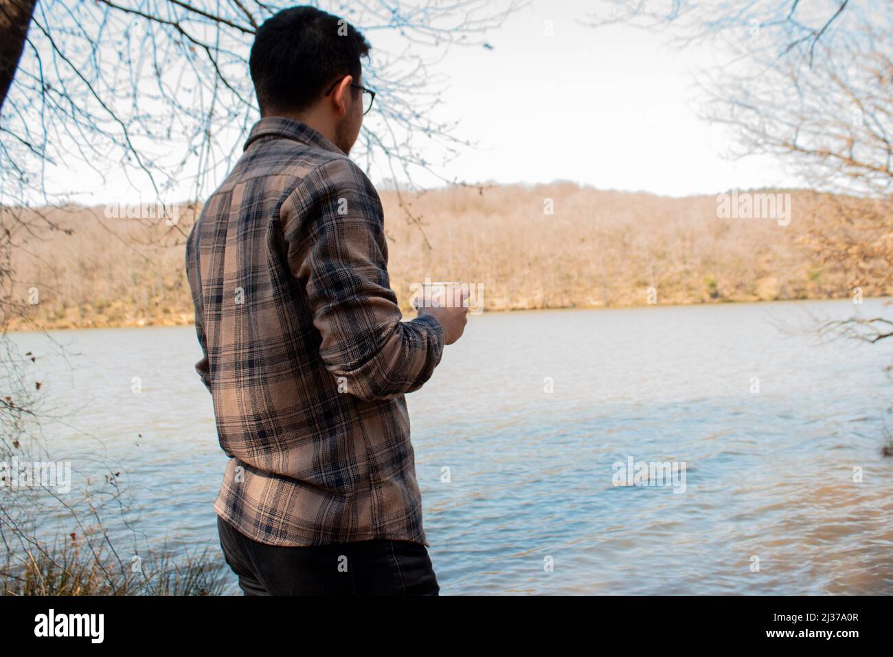 Homme buvant du thé et regardant au lac, pensant la personne avec une tasse de café dans la forêt, au lac et la personne avec une chemise de bûcheron Banque D'Images