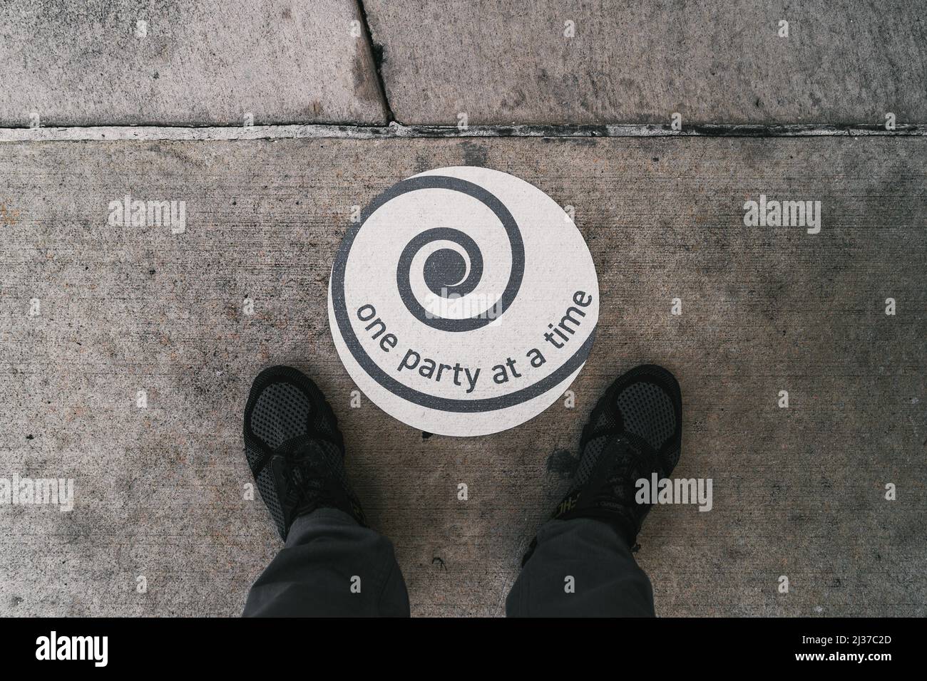 Vue de dessus d'un panneau avec le texte 'une partie à la fois' et les pieds mâles sur le sol Banque D'Images