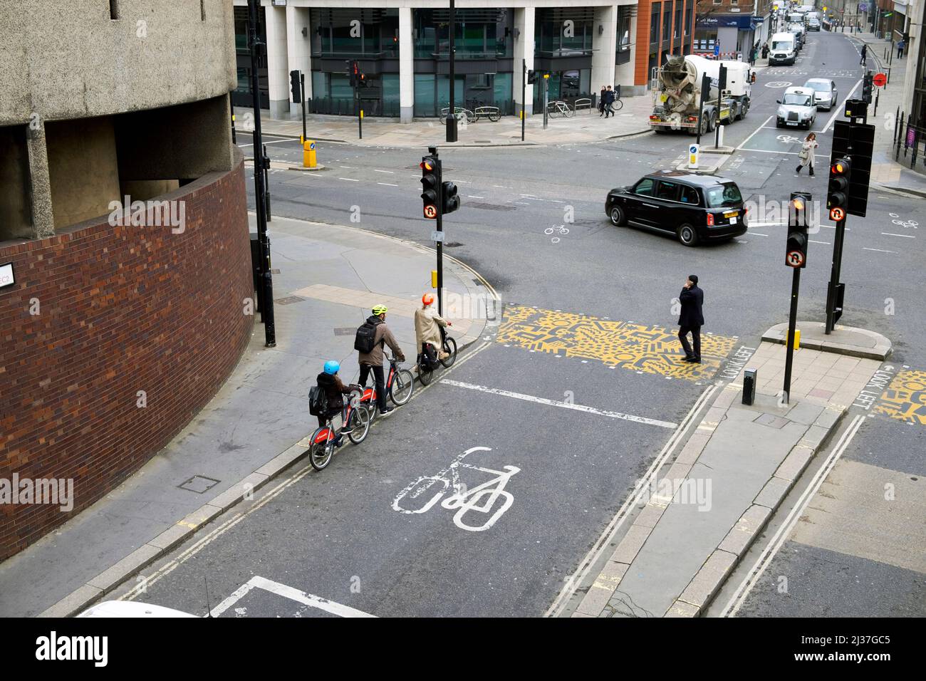 Famille attendant sur des vélos portant des casques de sécurité cyclistes attendant aux feux de circulation sur Beech Street et Aldersgate dans la ville de Londres KATHY DEWITT, Royaume-Uni Banque D'Images