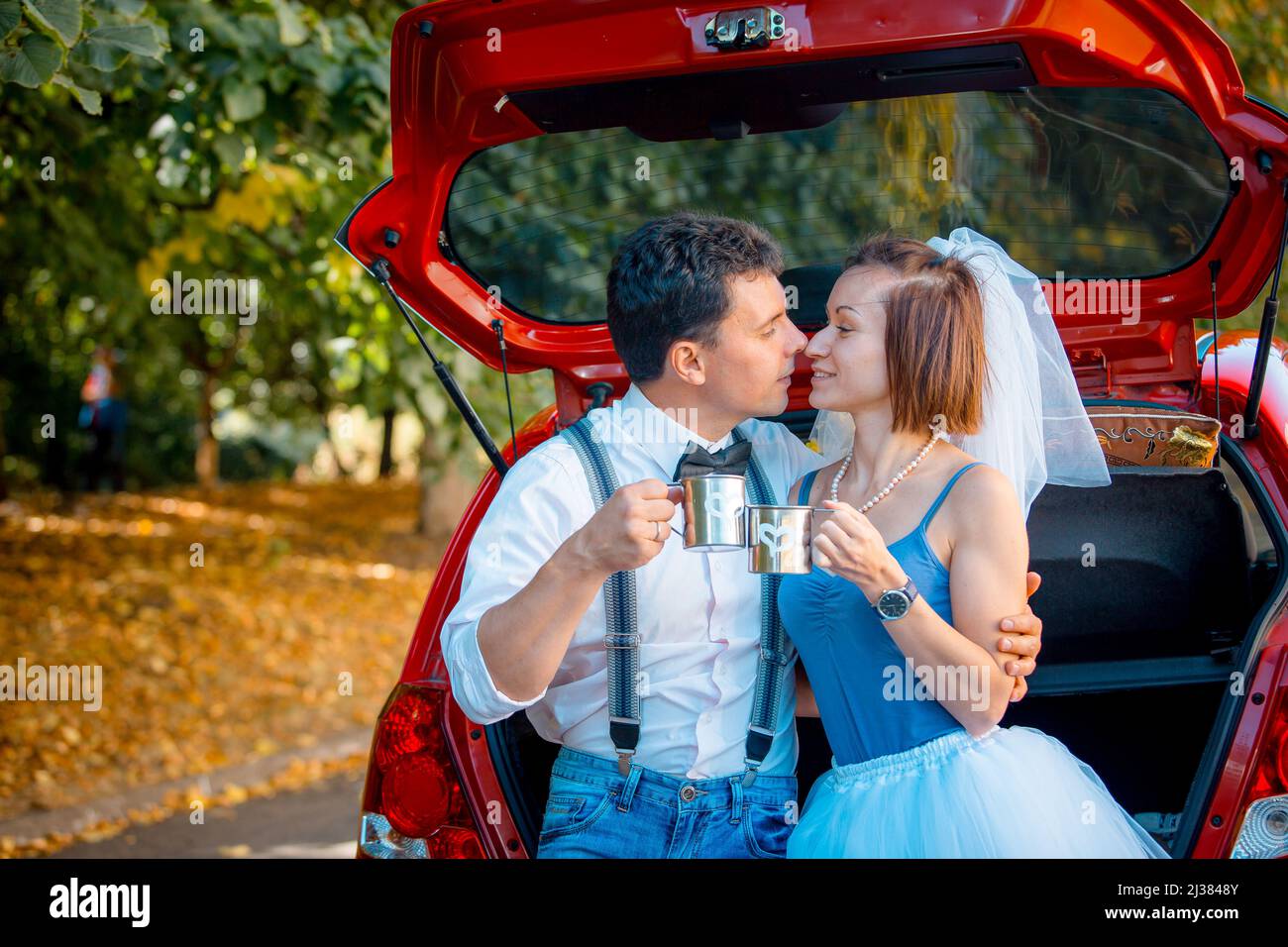 Portrait d'un jeune couple en tenue de mariage célébrant leur anniversaire  de mariage. Le couple lave la voiture. Sourire, baiser, amour Photo Stock -  Alamy