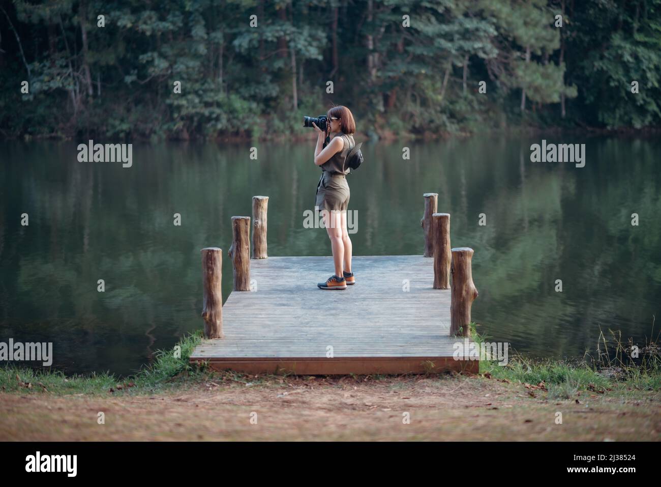 Une aventurière prend une photo du lac et de la forêt de pins sur le pont en bois. Banque D'Images