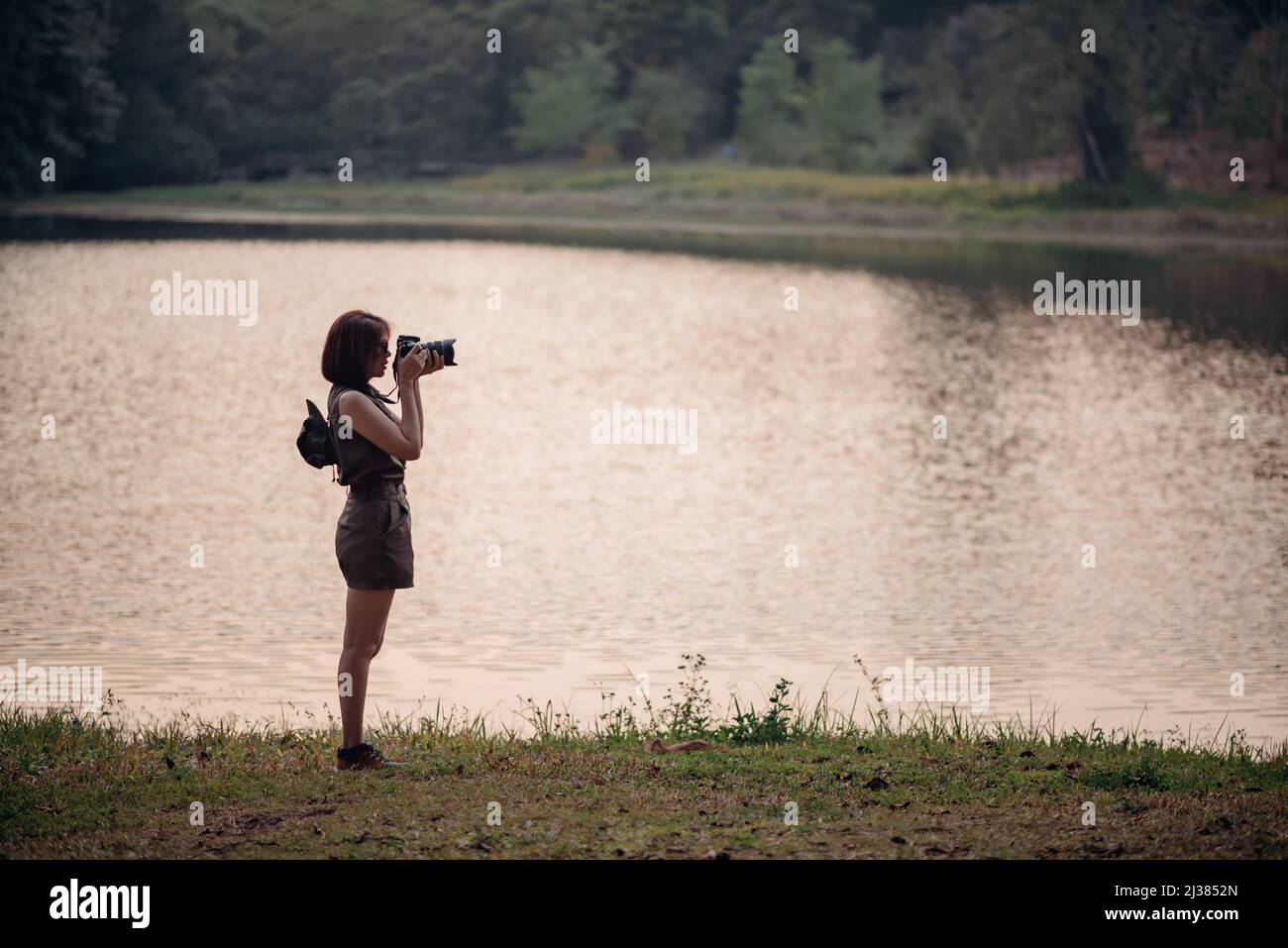 Une aventurière prend une photo du lac et de la forêt de pins. Banque D'Images