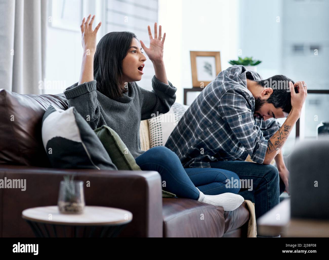 Le mariage est le sport d'équipe ultime. Photo d'un jeune couple qui a l'air contrarié tout en regardant la télévision ensemble à la maison. Banque D'Images