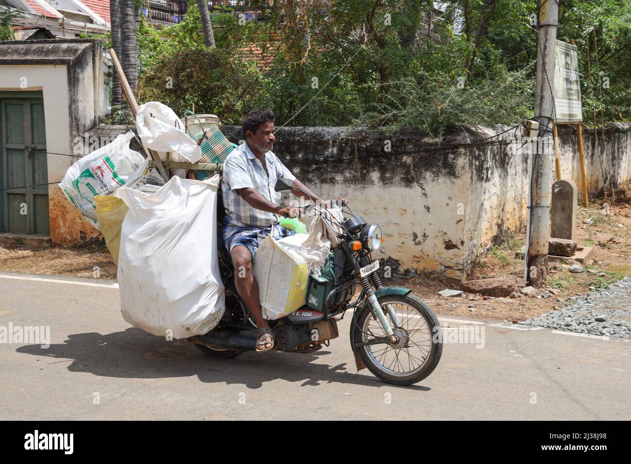Homme sur une moto surchargée à travers Kanadukathan, Chettinad, Tamil Nadu, Inde Banque D'Images