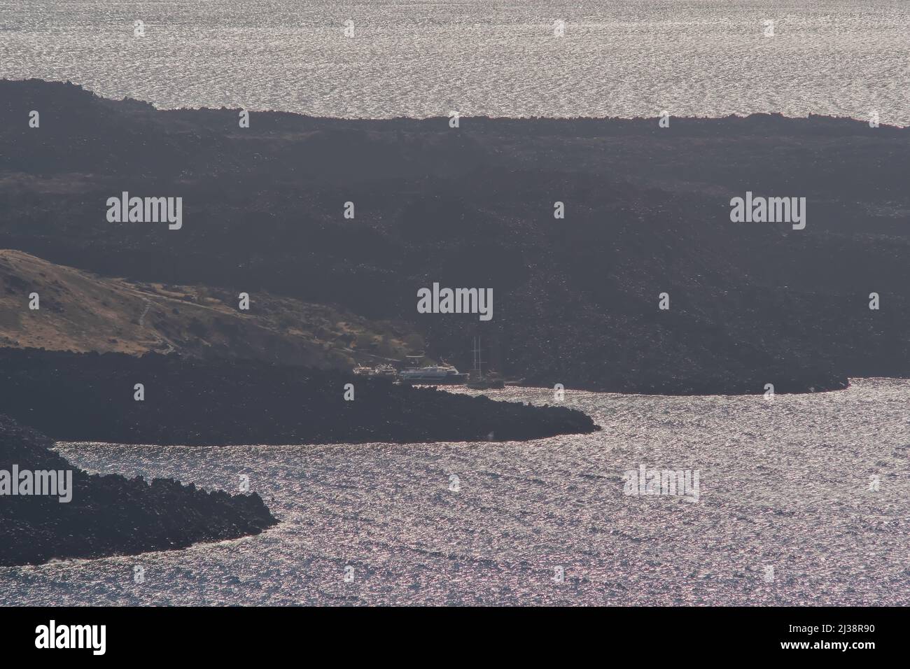 Vue rapprochée sur le volcan de Santorin, Nea Kameni et son petit port avec ferries et bateaux Banque D'Images