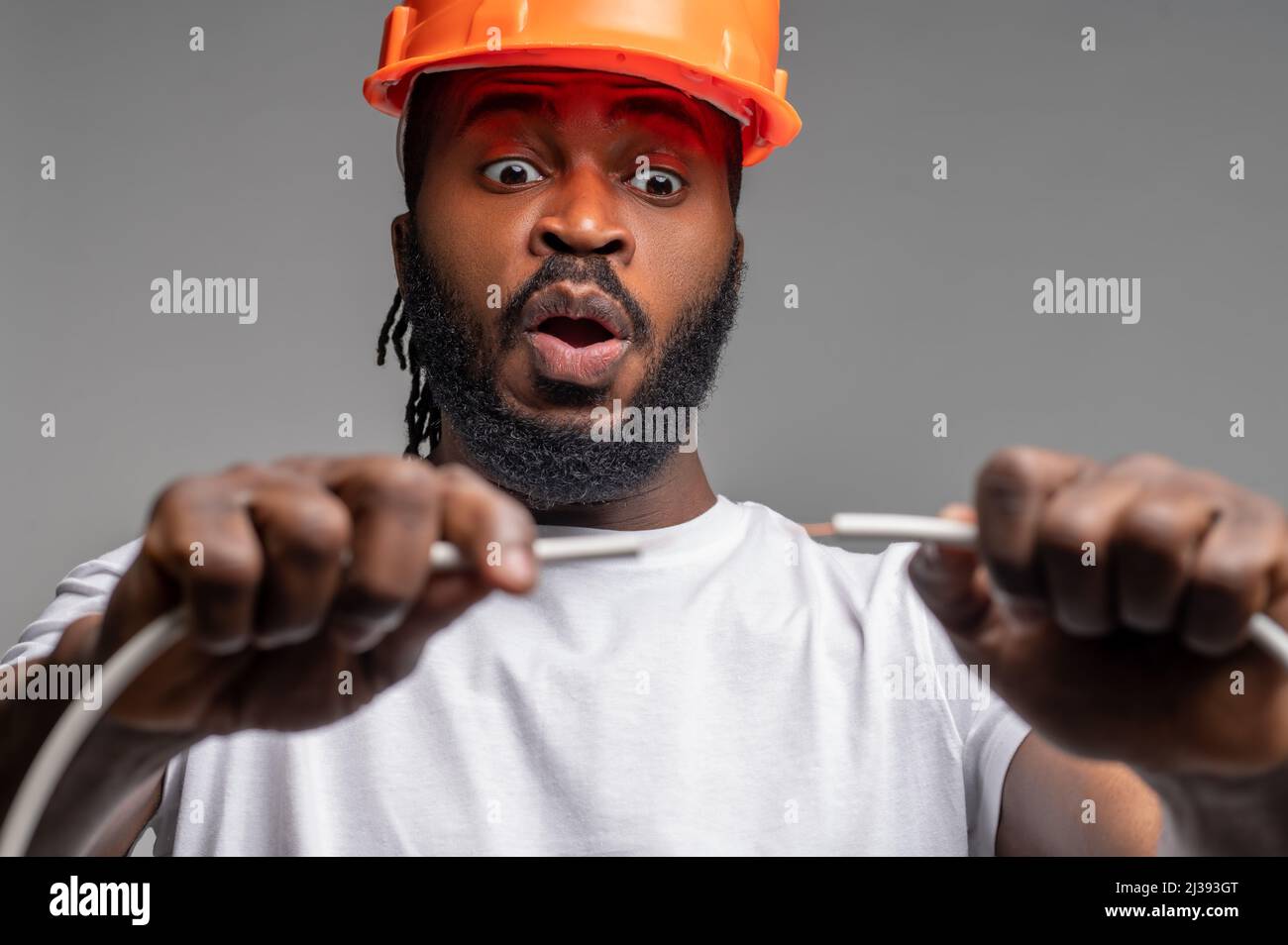 Jeune électricien dans un casque orange expérimentant le câblage électrique Banque D'Images