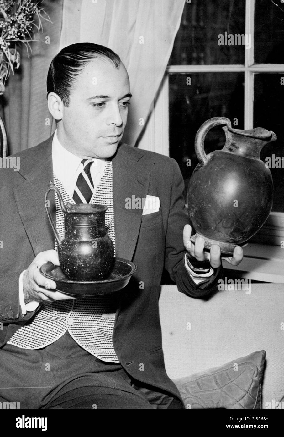 Actor ajoute B.C. Pottery à sa collection - l'acteur Herbert LOM vu dans son appartement de Kensington (Londres) regardant fièrement les pièces de poterie étrusque qu'il a récemment acquises pendant le tournage à Rome. Sur la gauche se trouve une tasse à boire et un plateau (4th. Century B.C.) et sur la droite de la verseuse (5th. Century C.-B.). L'acteur Herbert LOM recueille des antiquités comme un passe-temps et, tout en filmant récemment en Italie pour la « Guerre et paix » de Tolstoy, dans laquelle il joue le rôle de Napoléon, il a fait quelques ajouts très précieux à sa collection croissante. 25 novembre 1955. (Photo de Fox photos). Banque D'Images