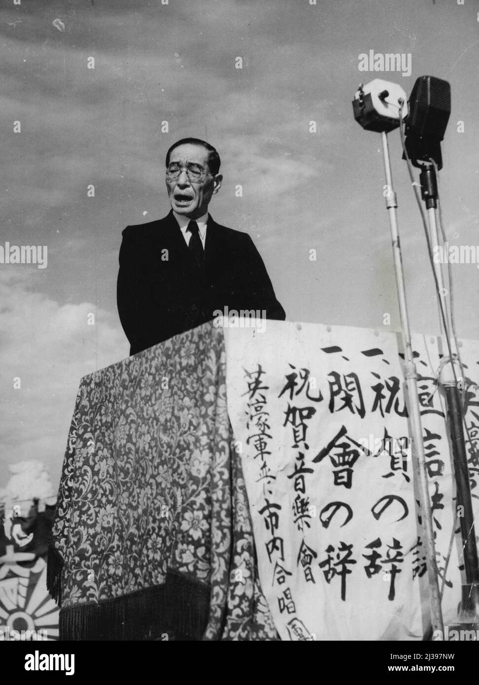 Le gouverneur de la préfecture d'Hiroshima lisant la renonciation du Japon à la guerre promulgue en vertu de la nouvelle Constitution, aux citoyens d'Hiroshima lors d'une cérémonie qui a eu lieu à ***** Sanctuaire sacré japonais à 300 mètres d'où ***** La bombe atomique a explosé. Orphelins dont ***** Ont été tués par la bombe atomique assisté à la cérémonie. Les sélections ont été jouées par le 67 Batt. Bande australienne pendant la cérémonie. 18 novembre 1946. Banque D'Images