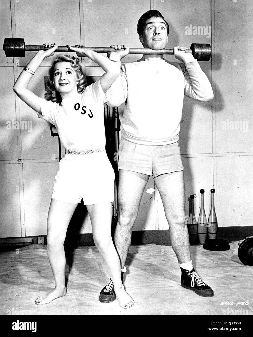 C'est Une cour d'Hollywood! Il y a toutes sortes de façons de woo une fille, comme tout le monde le sait, mais laissez-le à Hollywood pour en trouver une nouvelle. Edmund O'Brien, qui a joué le rôle d'« un acte de meurtre » au studio Universal-International, a été ravi lorsque Olga San Juan, sa version bêta, a déménagé dans le même studio pour apparaître dans « One Touch of venus » et « Comtesse de Monte Cristo ». Cela signifiait qu'Edmund et Olga seraient ensemble beaucoup - même dans le gymnase de studio. C'est alors que la cour utilise à la fois le charme et les muscles: Qui soutient la cloche de bar? Les gymnastes vous diront que vous devez être amoureux de vouloir Banque D'Images