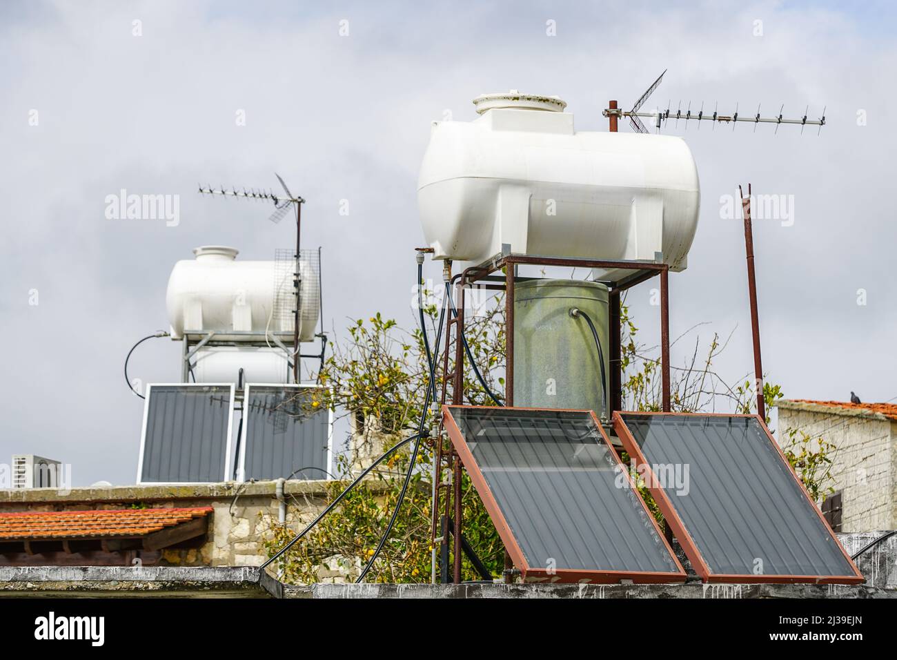 Systèmes de chauffage solaire de l'eau avec de grands réservoirs d'eau et des chaudières sur le toit de la maison, ainsi que des antennes de télévision analogiques Banque D'Images