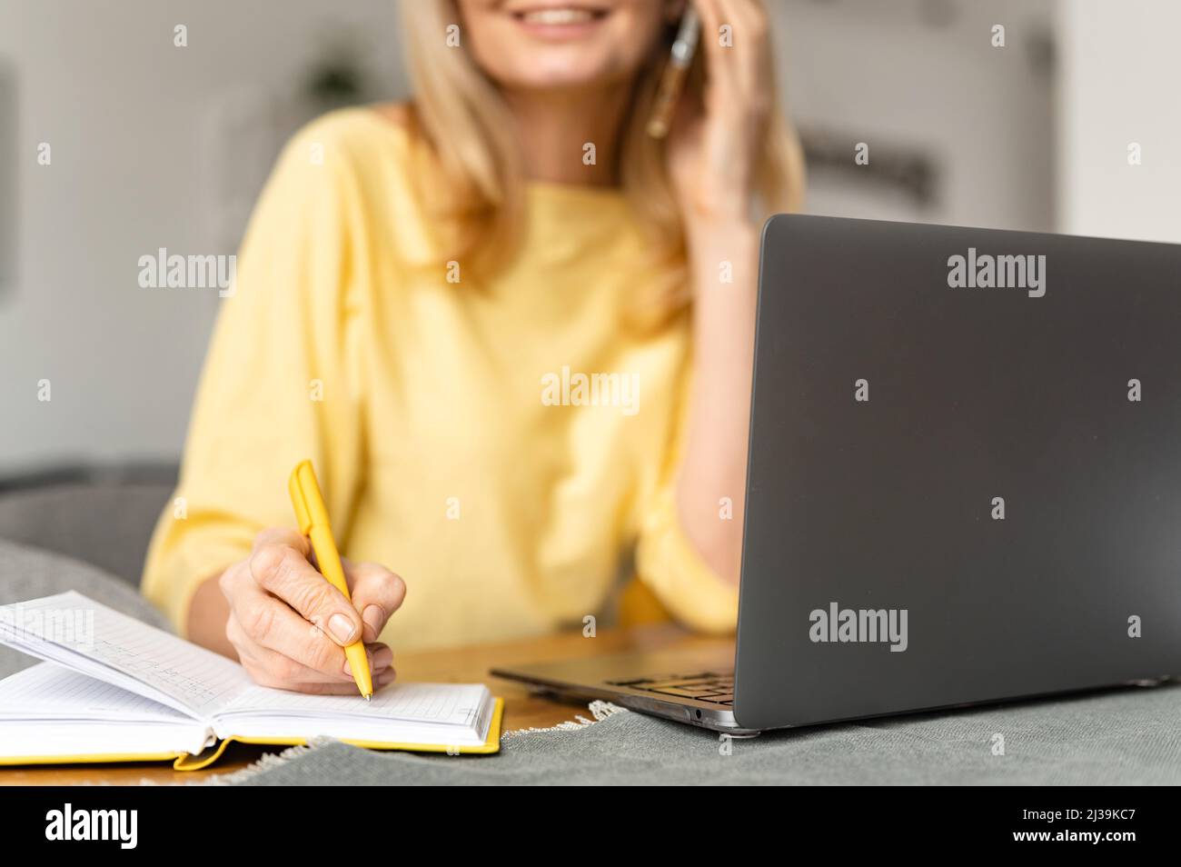 Vue rognée de la femme d'affaires avec un bossy ayant une conversation téléphonique travaillant avec un ordinateur portable au bureau. Une femme de vente qui parle avec un client par téléphone intelligent Banque D'Images