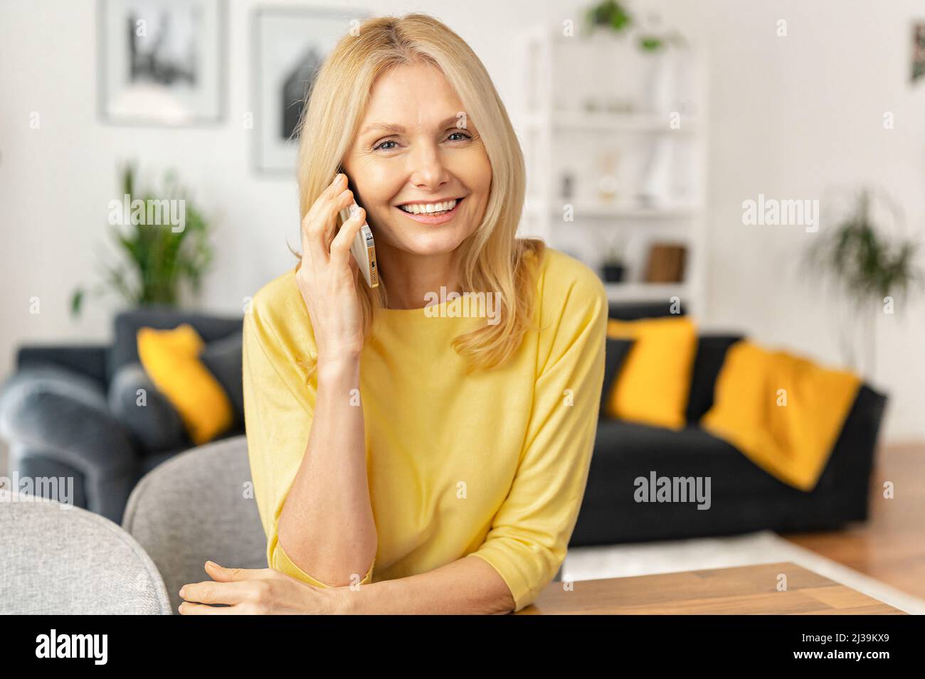 Heureuse femme âgée bénie parlant sur téléphone mobile et riant, exprimant des émotions positives. Une femme d'affaires joyeuse a une conversation agréable Banque D'Images