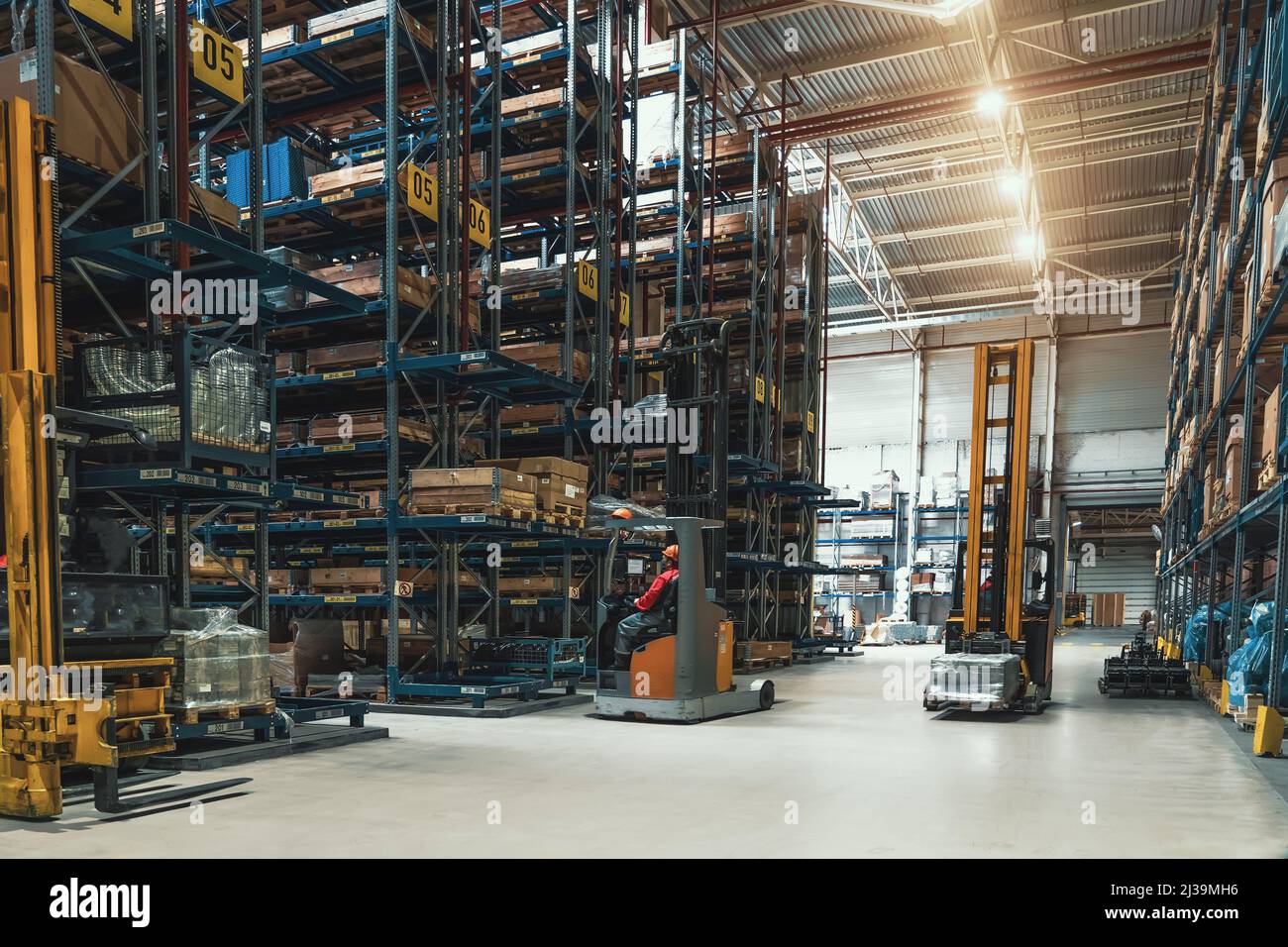 Entrepôt de la société logistique avec chariots élévateurs. Grand magasin de distribution avec étagères hautes. Banque D'Images