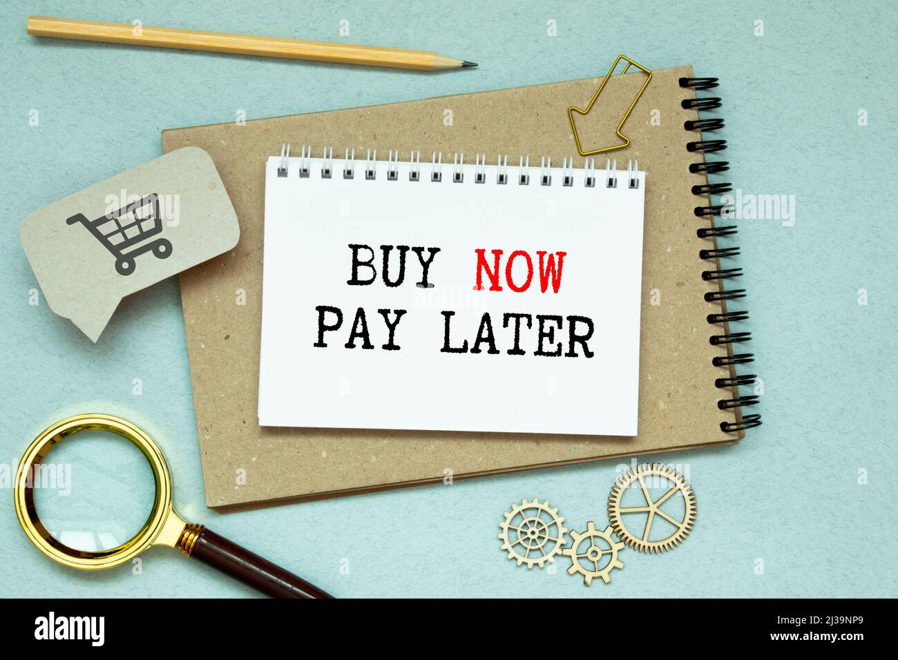 Sur une table blanche se trouve une calculatrice, une clé de voiture, de l'argent, un stylo et un bloc-notes avec l'inscription ACHETER MAINTENANT - PAYER PLUS TARD. Banque D'Images