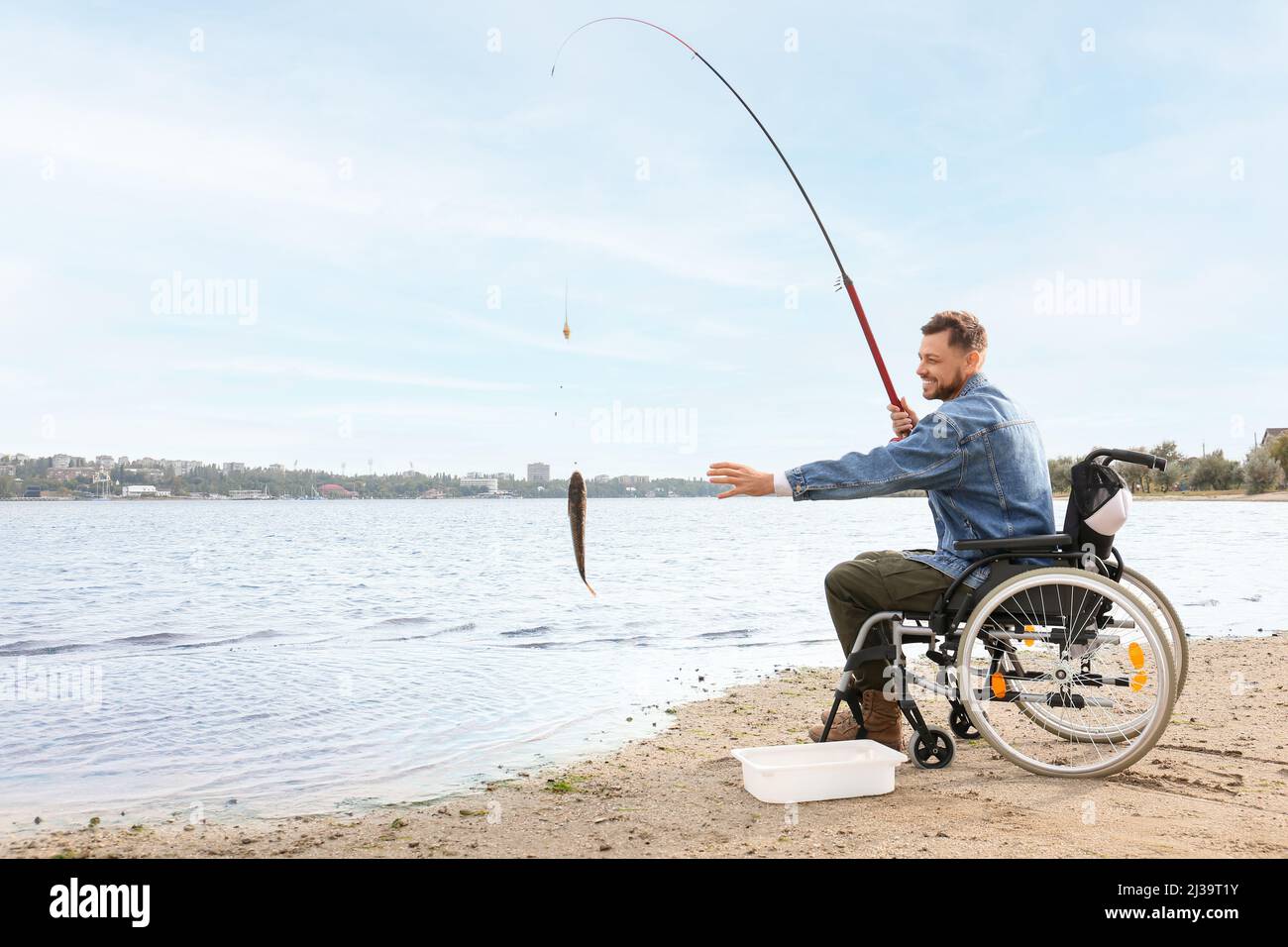 Homme en fauteuil roulant, pêche sur la rivière Banque D'Images