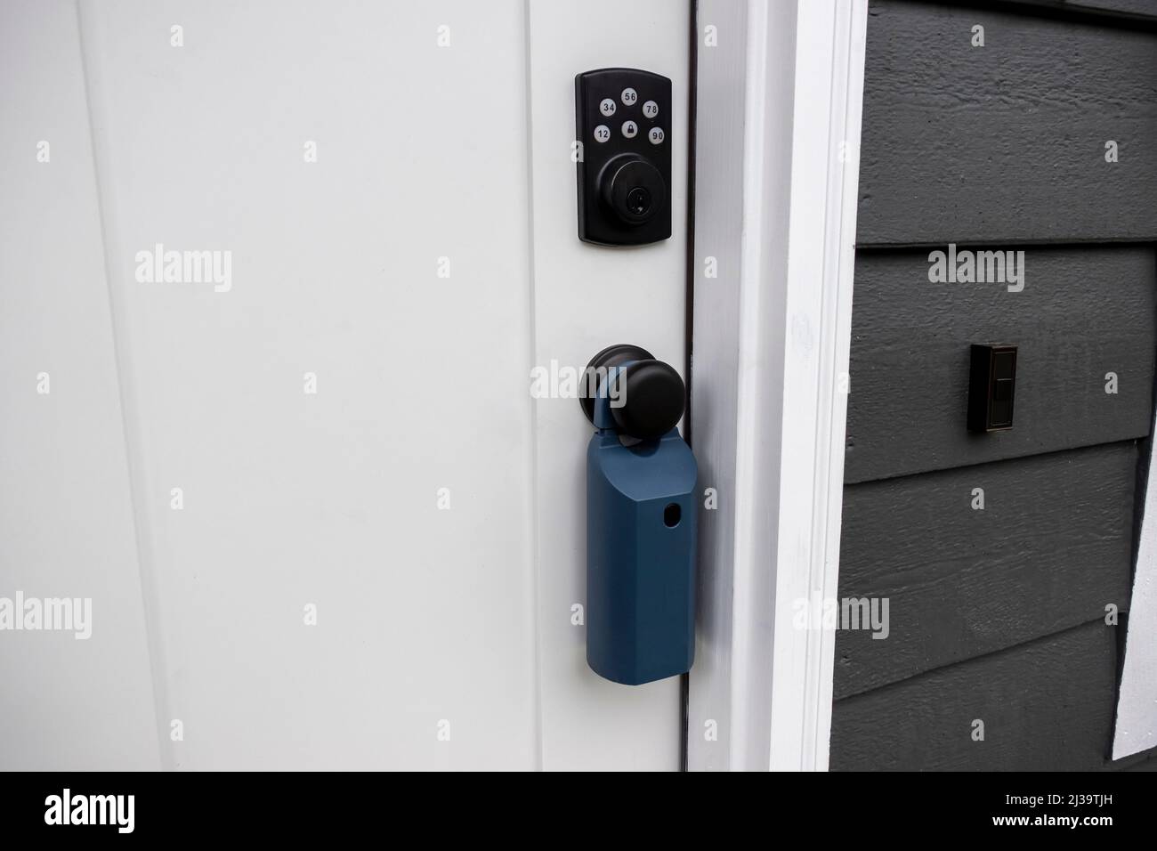 Vue d'une porte blanche avec entrée clavier et d'un boîtier de verrouillage immobilier autour du bouton de porte Banque D'Images